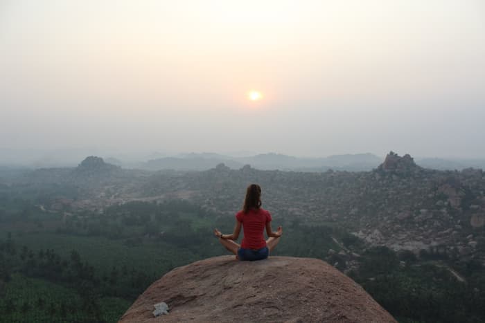 Seated in meditation on a boulder at sunrise