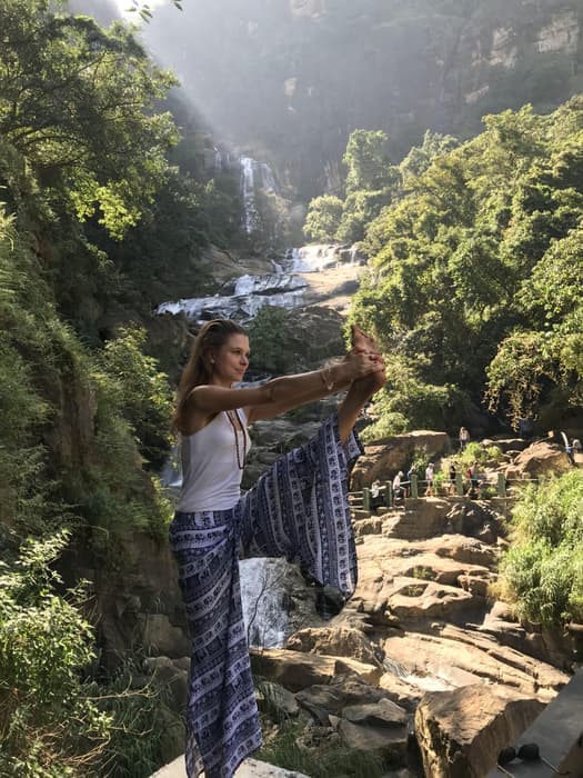Standing bound pose in front of a jungle waterfall