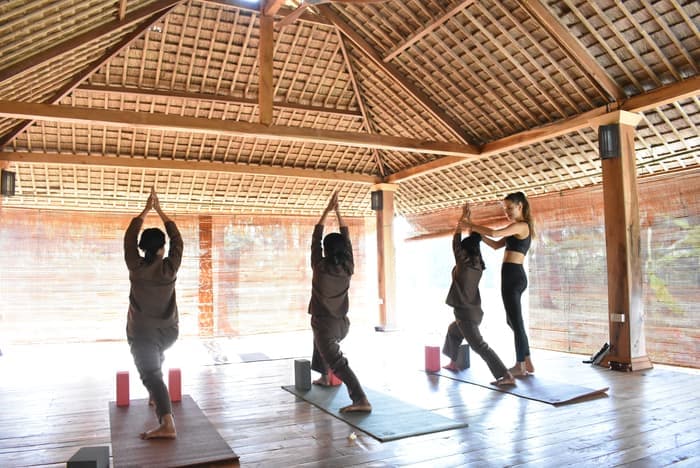 A class practising together in an open-sided wooden shala