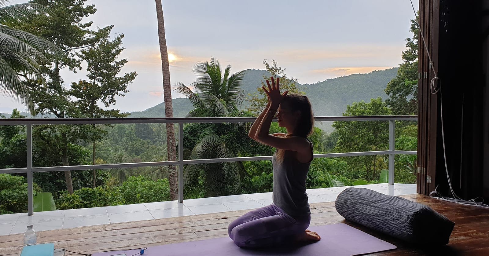 Seated in meditation on a deck looking out to the hills