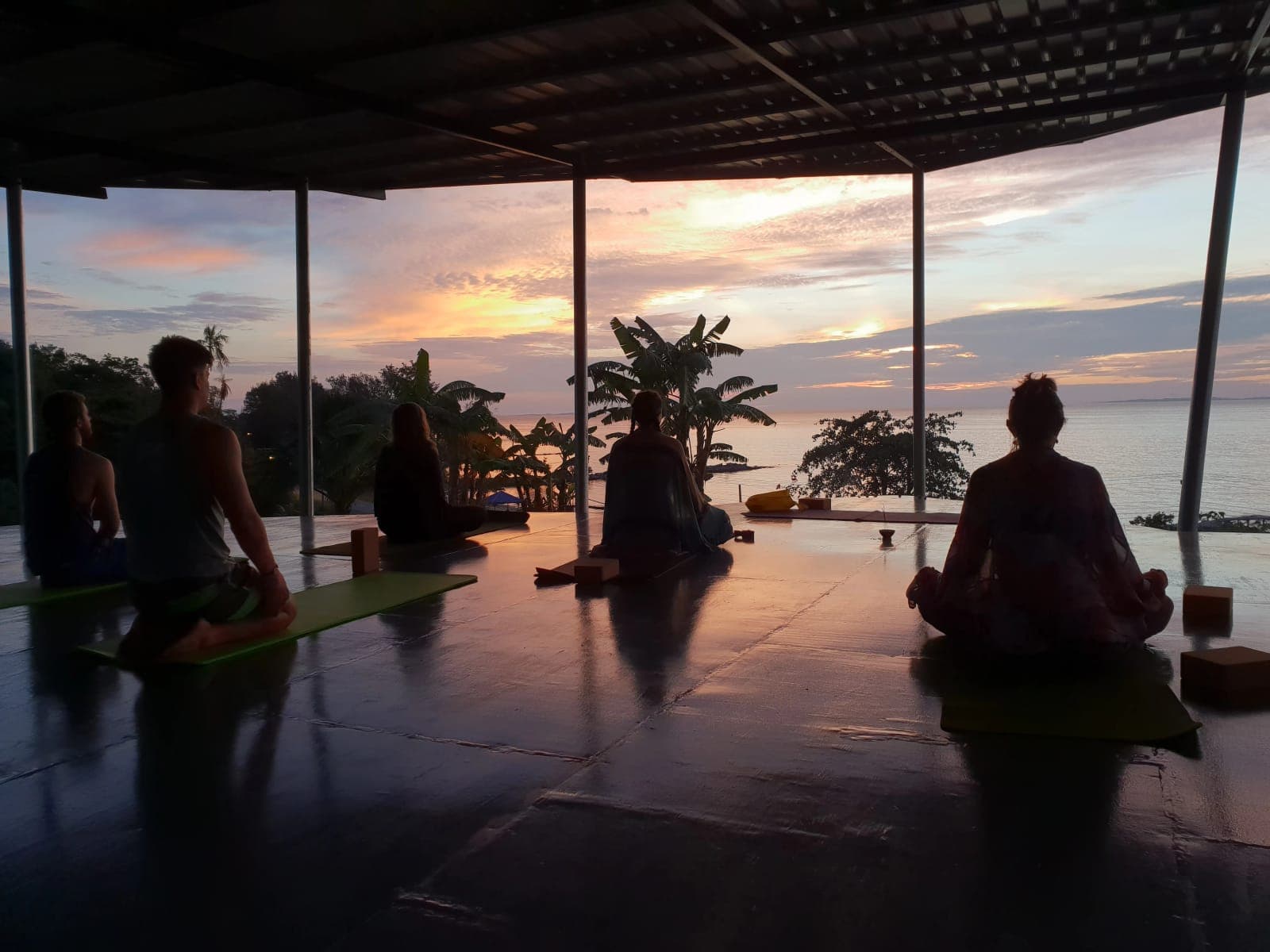 Silhouettes practising in an open shala at sunset
